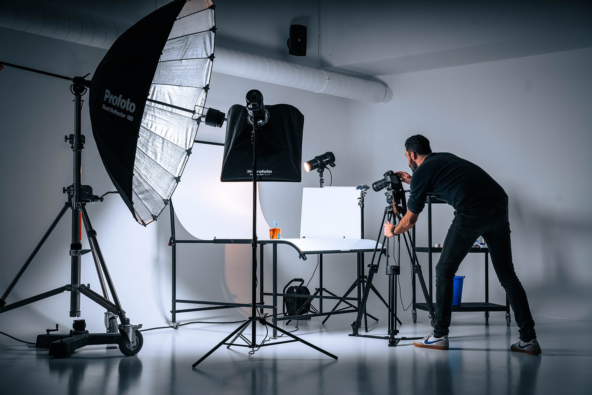 Een man die een foto neemt van een fles in een professionele fotostudio