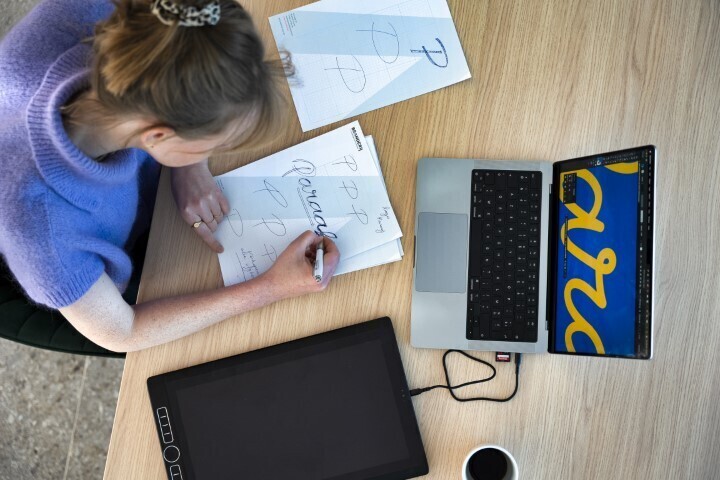 Vrouw is een logo aan het uittekenen achter haar laptop