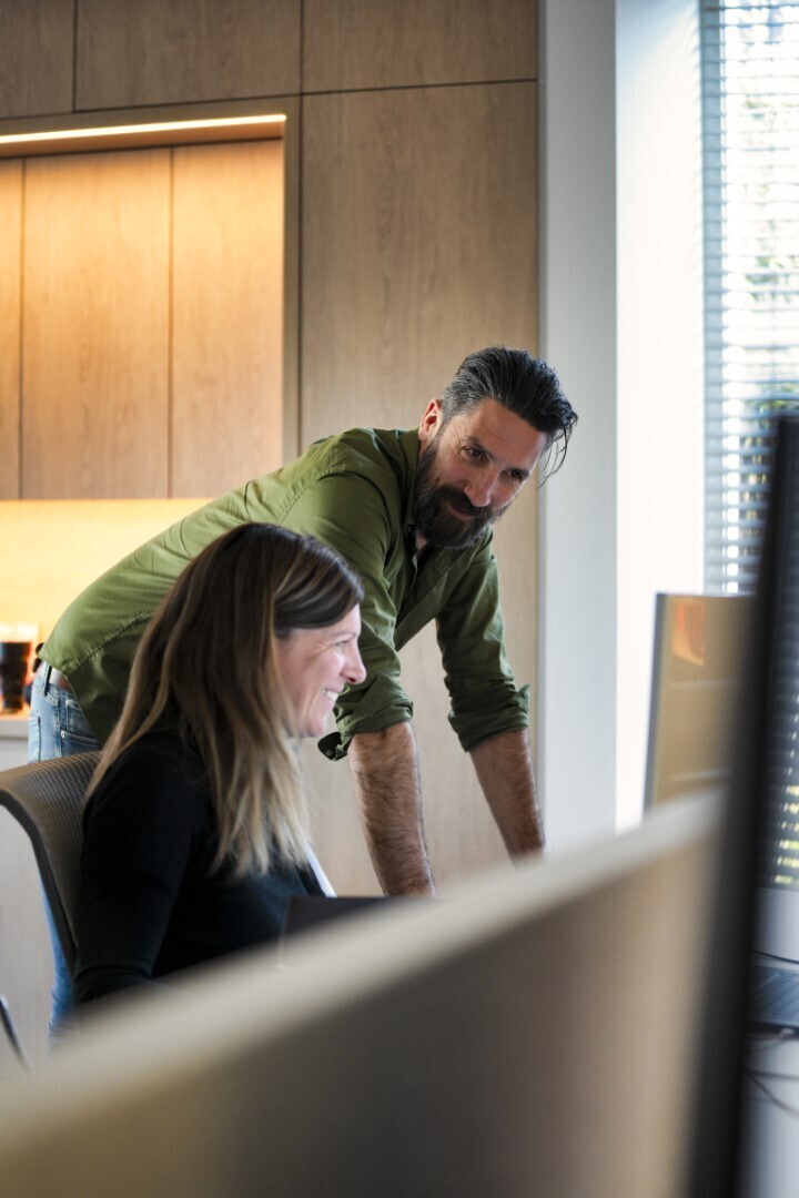 Man in een groen hemd die kijkt naar een vrouw die kijkt naar een computerscherm