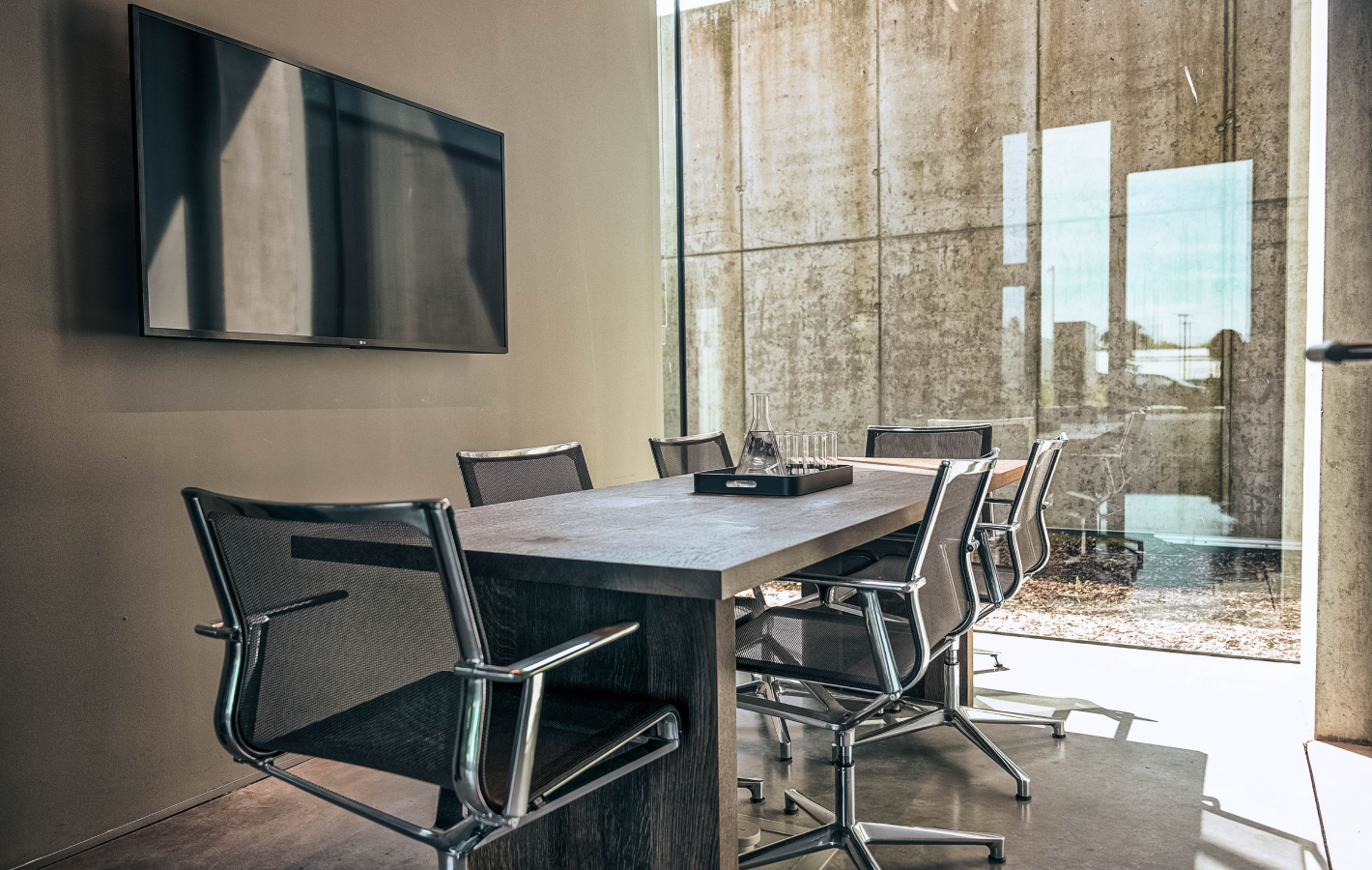 Een luxe meetingroom met grote raampartijen, een grote tafel met 6 stoelen, een groot scherm aan de muur